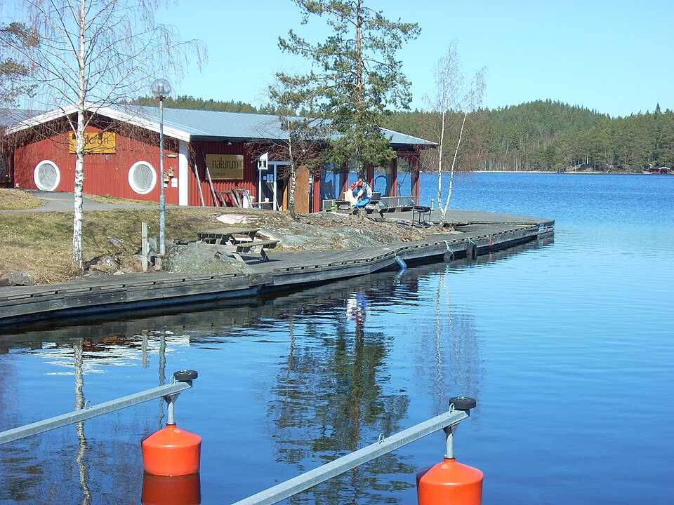 View of the building of Naturum Sommen next to the lake Sommen. A pine and spruce forest can be seen in the background. Birches in the picture have still not opened it leaves.