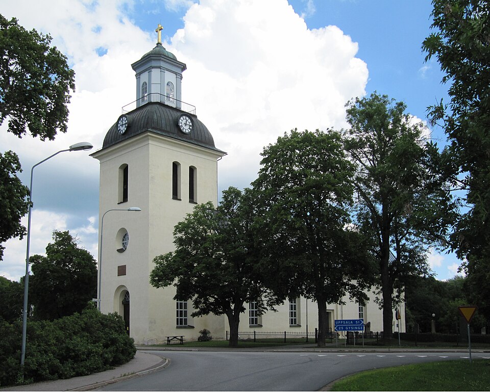 Östervåla kyrka. Länsväg 272 passerar framför kyrkans ingång i väster.