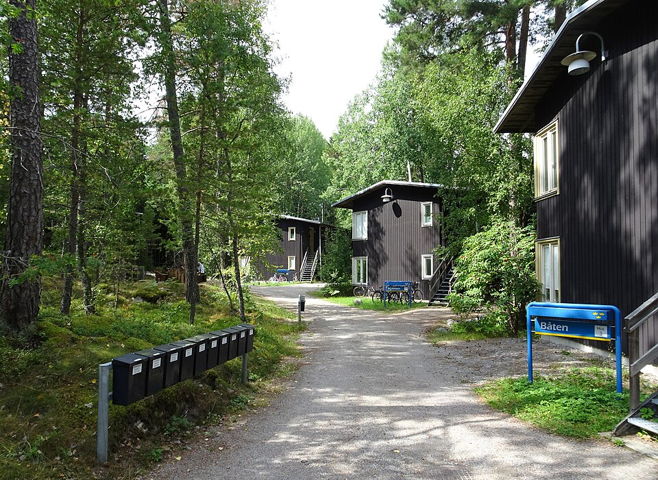 Studentbostäder på Bosön, ritade av arkitekterna Kjell Forshed och Björn Dahlberg 1999. ”Husen ska stå rakt ner i blåbärsriset!”. Ingår i Riksidrottsförbundets utvecklingscentrum. Till vänster brevlåd
