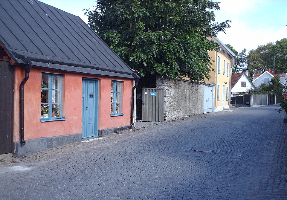 Södra Murgatan, where St Mikael Church stood, Visby, Sweden. The red building is Södra Murgatan 31. The next building is Södra Murgatan 35, at the crossing with Tunnbindaregatan (one-way street sign).