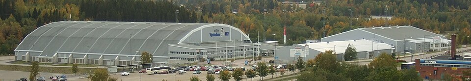 Panoramic view from east-northeast of Gärdehov sports/fair centre, Sundsvall, Sweden. Nordichallen (trade fairs & indoor soccer) to the left, Gärdehallen (ice hockey & figure skating) to the right beh